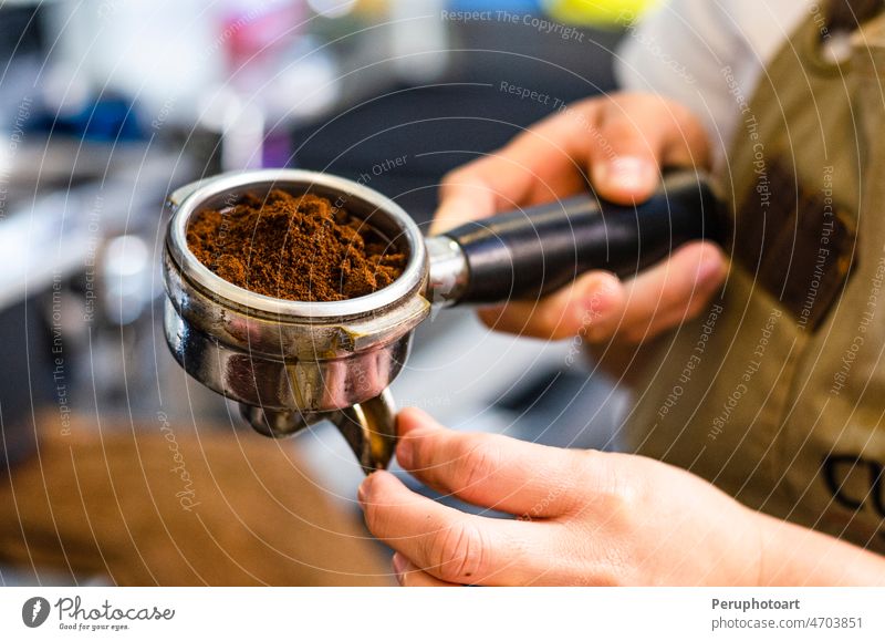 Nahaufnahme eines weiblichen Barista, der gemahlenen Kaffee für die Zubereitung von Espresso in der Hand hält. sich[Akk] zu schaffen machen Portafilter