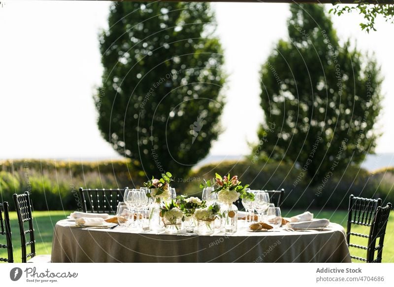 Banketttisch mit Weingläsern und Blumen Tabelleneinstellung Weinglas Glaswaren Blumenstrauß Feiertag Festessen Landschaft Geschirr Hochzeit Anlass Hinterhof Hof