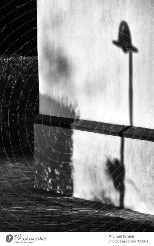 Schattenlaterne an einer Hauswand Schwarzweißfoto Schwarz und weiß schwarz Außenaufnahme Licht tiefstehende sonne Schattenspiel Schattenwurf