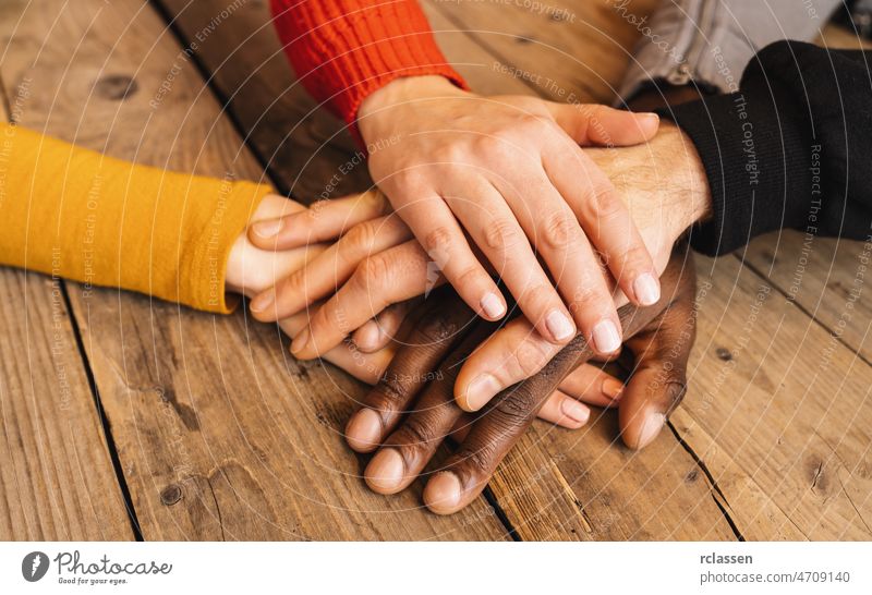 Verschiedene Hände sind auf dem Holztisch zusammengefügt Zusammensein vielfältig Kinder Jugend Teamwork Gemeinschaft Menschen abstützen Kindheit Familie