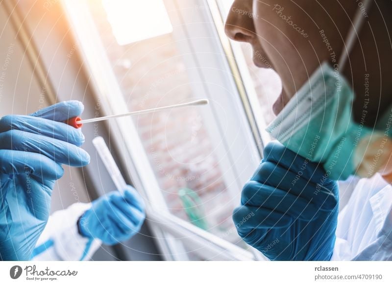 Mediziner in Schutzkleidung nimmt während der Coronavirus-Epidemie im Covid-19-Testzentrum COVID-19 Abstrichröhrchen aus dem Mund. Ablauf des PCR-DNA-Testprotokolls.