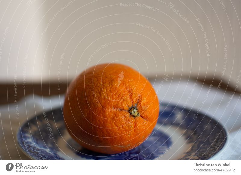 Eine Bio-Orange auf einem weiß-blauen Teller Bio-Apfelsine Bioprodukte Orange (Frucht) Obst Bioobst Ernährung gesund lecker frisch saftig unbehandelt