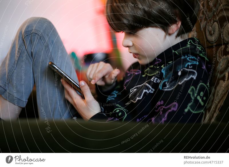 Kind mit Smartphone Handy Junge Erziehung Medienpädagogik digital Mediennutzung sitzen Sofa Innenaufnahme Konzentration whatsapp 3-8 Jahre Wohnzimmer Alltag