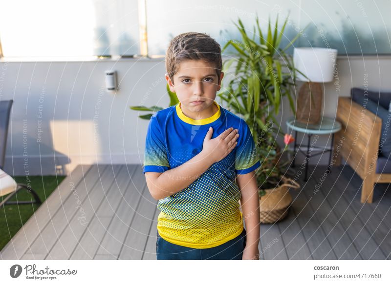 Kleiner Junge mit einem Ukraine-T-Shirt betet für sein Land blau Kaukasier Kind Konflikt Kultur beschädigte Geschichte bestickt Stickereien Fahne Fußball