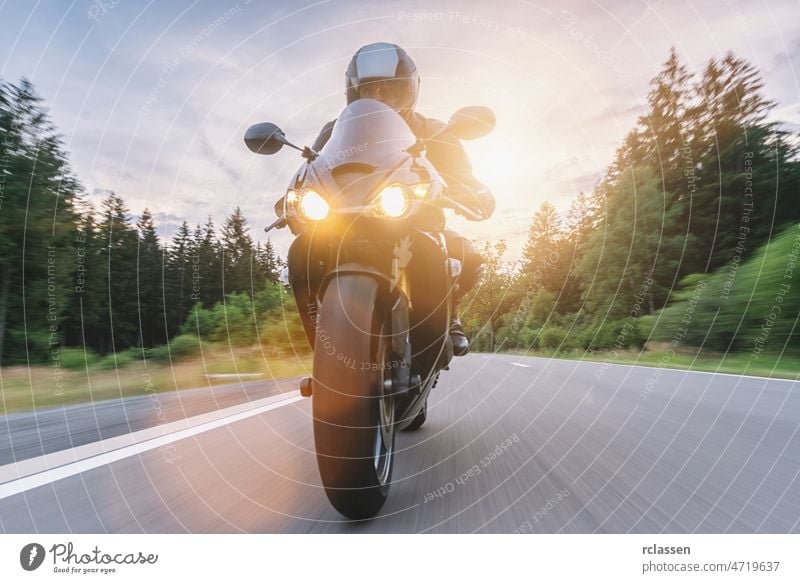 Motorradfahren bei Sonnenuntergang auf der leeren Straße bei einer Motorradtour. copyspace für Ihren individuellen Text. Fahrrad Spaß Jacke Abenteuer Asphalt