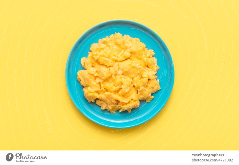 Rührei in einem blauen Teller, Draufsicht auf einen gelben Tisch. oben Amerikaner Hintergrund Frühstück hell Brunch Nahaufnahme Farbe Textfreiraum cremig Küche