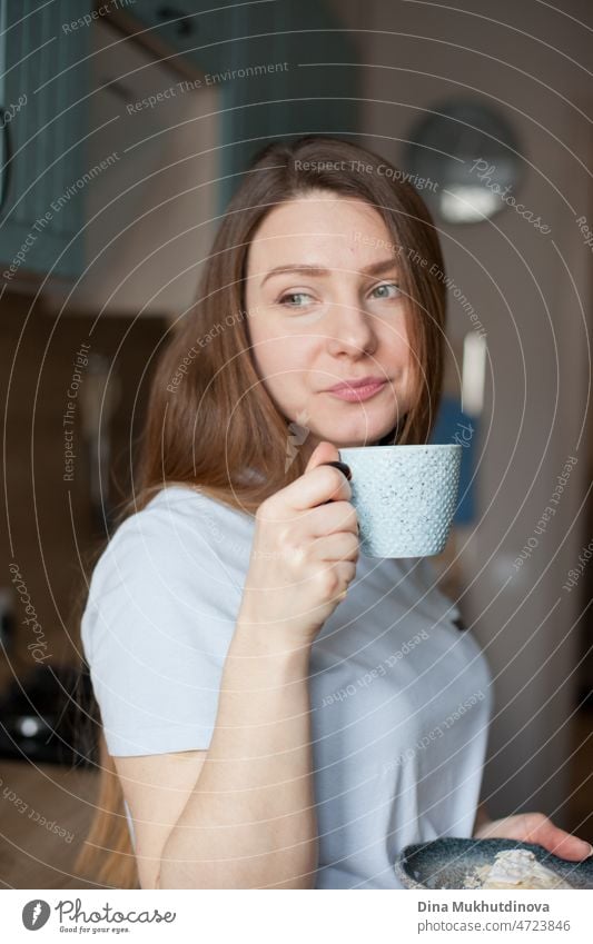 junge Frau trinkt morgens Kaffee aus einer Keramiktasse und lächelt in den neuen Tag Morgen gute Miene zum bösen Spiel trinken offen echte Menschen Lifestyle