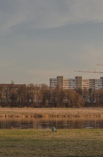 Person sitzt alleine am Elbufer in Dresden Einsam Einsamkeit Städtereise Ferien & Urlaub & Reisen Elbe Alleinsein Depression sitzen Flussufer Stadt Winter