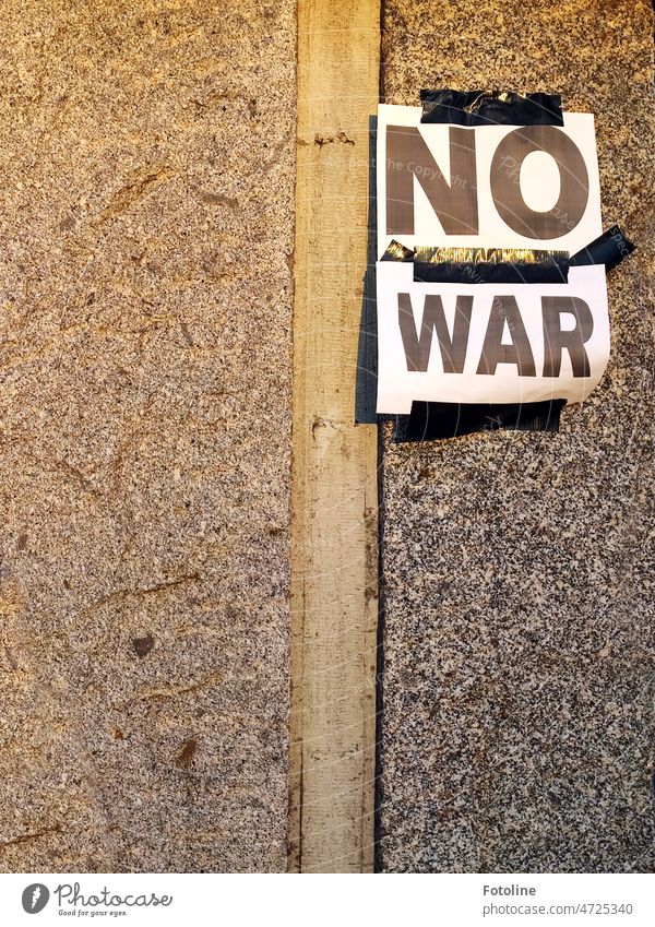 "NO WAR" steht auf den weißen Blättern, die mit schwarzem Klebeband an die Mauer geklebt wurden. Schrift Text Buchstaben Wort Schriftzeichen Typographie Wand