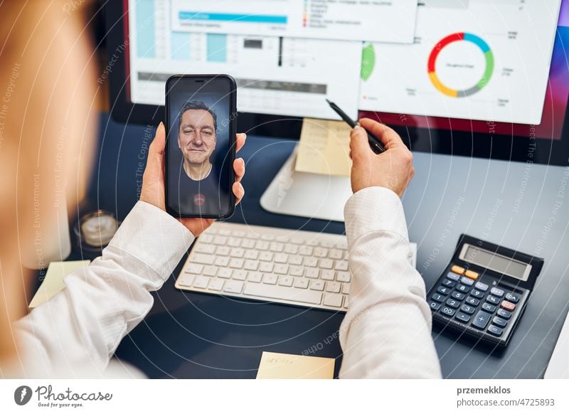 Unternehmerin führt mit ihrem Geschäftspartner einen geschäftlichen Videochat auf dem Smartphone. Geschäftsfrau arbeitet mit Daten in Diagrammen, Grafiken und Diagrammen auf dem Computerbildschirm