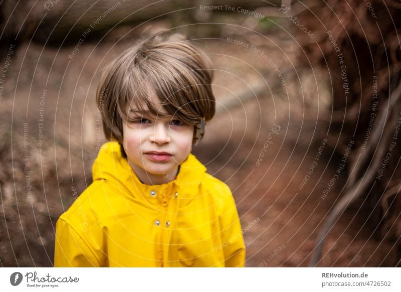 Kind im Wald mit Regenjacke Tag Umwelt authentisch Herbst Jacke Junge im Freien Spielen Natur Mensch Kindheit erkunden Zentralperspektive Unschärfe nachdenklich