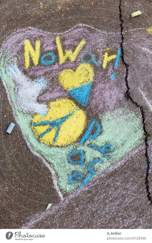 Schriftzug No War mit Peace Symbol und einer Taube für den Frieden auf Asphalt mit farbiger Kreide gemalt Schriftzeichen Krieg Solidarität Konflikt