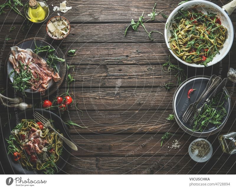 Grüne Nudeln auf Tellern, Zutaten und Küchenutensilien mit Parmaschinken, Tomaten, Rucola grün Spätzle Platten Utensilien Käse Olivenöl Italienische Küche