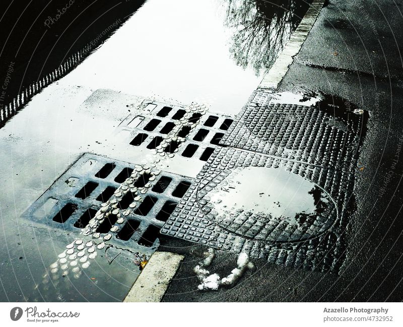 Wasser fließt in den Kanalisationsschacht. Nasse Straße mit Kanalisationsschächten. abstrakt Asphalt Allee Hintergrund helles Sonnenlicht kreisen Großstadt