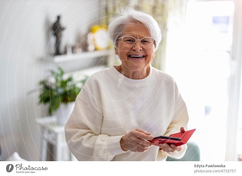 Porträt einer lächelnden älteren Frau zu Hause Brille allein häusliches Leben Oma Großmutter graue Haare heimwärts im Innenbereich Lifestyle reif alt