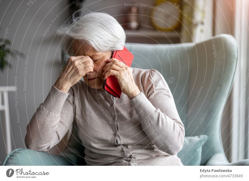 Ältere Frau empfindet Schmerzen, während sie ihren Arzt über ihr Smartphone konsultiert allein zu Hause häusliches Leben älter Oma Großmutter graue Haare