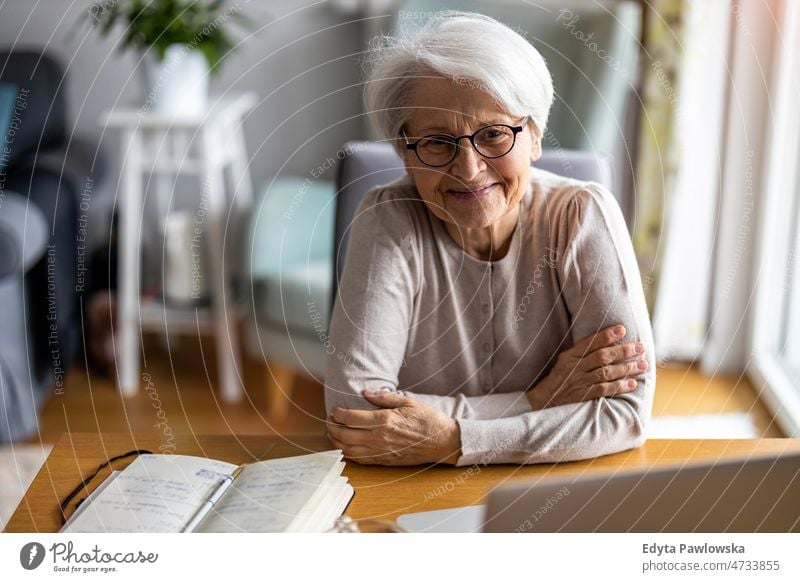 Porträt einer lächelnden älteren Frau zu Hause Brille allein häusliches Leben Oma Großmutter graue Haare heimwärts im Innenbereich Lifestyle reif alt