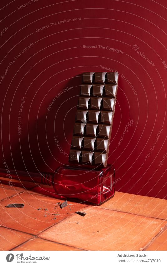 Schokoladentafel auf Glas in der Nähe der roten Wand süß Flasche bröckeln Stock Kakao Lebensmittel Zucker lecker geschmackvoll Dessert Kalorie appetitlich