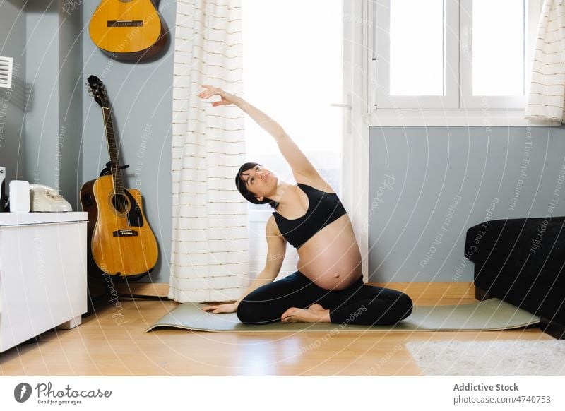 Schwangere Frau beim Yoga zu Hause schwanger üben heimwärts Schwangerschaft erwarten beweglich Wegbiegung Bauch Dehnung Asana Gesundheit pränatal sitzen