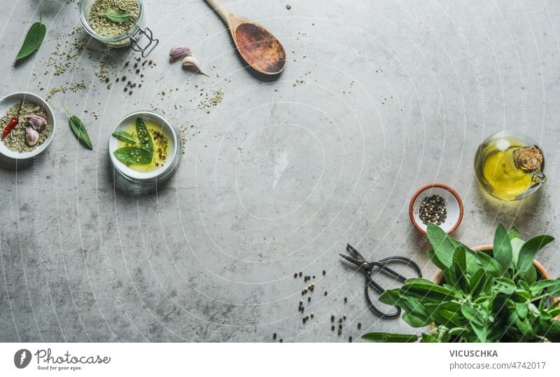 Essen Hintergrund mit geschmackvollen Zutaten auf grauem Beton Tisch. Ansicht von oben. Lebensmittelhintergrund Kräutersalz Salbei Olivenöl Gewürze hölzern