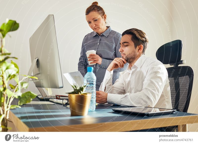 Zwei Geschäftsleute besprechen Finanzdaten am Computer. Geschäftsfrau arbeitet mit männlichen Kollegen im Büro. Menschen Unternehmer arbeiten mit Diagrammen und Tabellen auf dem Bildschirm. Zwei Menschen arbeiten zusammen