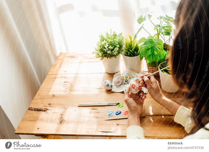 Weibliche Malerei eine moderne Ostereier. Pinsel und malt mit Blumen und Pflanzen. Glückliche Ostern Konzept auf einem hölzernen Hintergrund. Hände Hand Farbe