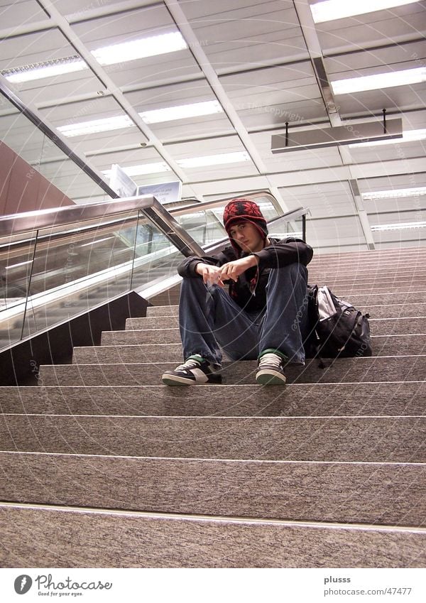 Gedankenversunken2 Stil Mensch Mann Erwachsene Jugendliche Flughafen Treppe Rolltreppe Mütze sitzen träumen warten Einsamkeit abgesondert leer Baseballmütze