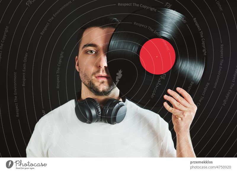 Mann hält Retro-Vinyl-Schallplatte, die das Gesicht bedeckt. Vintage-Musik-Stil. Mann hält Vinyl-Schallplatte auf dunklem Hintergrund. Retro-Musik Aufzeichnen