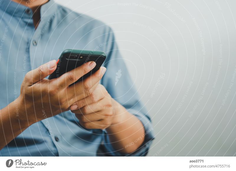Nahaufnahme eines Mannes, der sein Smartphone benutzt, um im Internet zu surfen, SMS zu versenden, einen SMS-Messenger oder Online-Banking zu nutzen. Handy