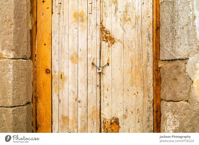 Verrostetes Vorhängeschloss, das eine alte Holztür mit einer Kette verschließt Tür hölzern Portugal tavira Fassade anketten Schloss Spind Taste Verlassen
