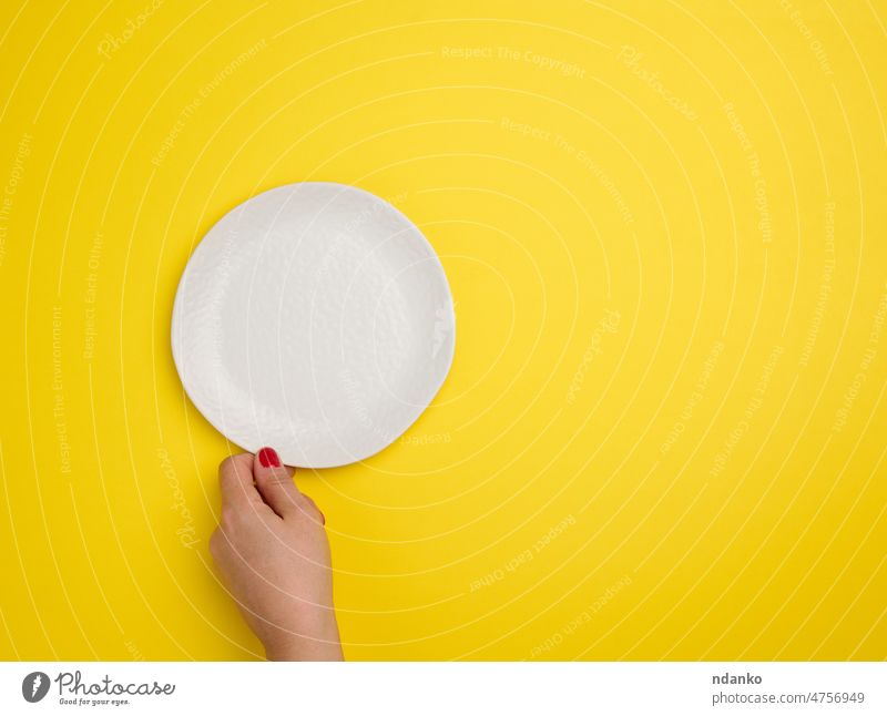 weibliche Hand, die einen weißen leeren runden Teller auf gelbem Hintergrund hält, Ansicht von oben blanko Schalen & Schüsseln Keramik kreisen Sauberkeit