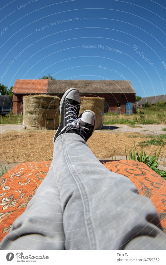 Beine mit grauen Jeans und Chucks auf einem Bauernhof relaxen Sommer Heu Stroh Landleben prignitz ländlich Landschaft Natur Außenaufnahme Ernte Ackerbau