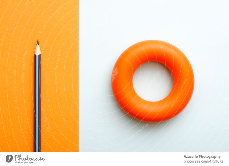 Orange Gummi Hand Greifer und ein Bleistift. Gesunder Lebensstil körperliche Aktivität Konzept flach legen. Muskelkraft gymnastisch Plan Gesundheit Lifestyle
