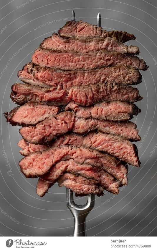 Scheiben eines Steaks auf weißem Hintergrund Steakscheibe Fleischgabel Metzger Grill Aufgespießt FLeischspieß Fett gegrillt selten isoliert