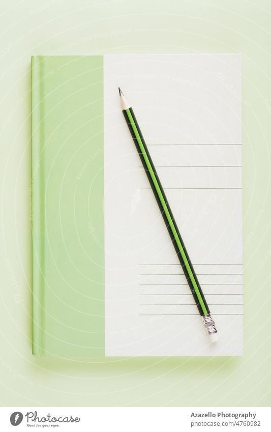 Grünes weißes Notizbuch mit einem Bleistift. Business Bildung minimalistisches Konzept flach legen. Notebook Notizblock Papier zeichnen Farbe schreiben Notizen