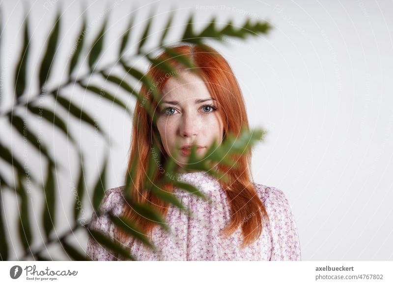 Frau versteckt sich hinter Zimmerpflanze Palmenblätter mittlerer Erwachsener Palmblatt versteckend Gesicht hinten im Innenbereich Pflanze Porträt Mädchen Person