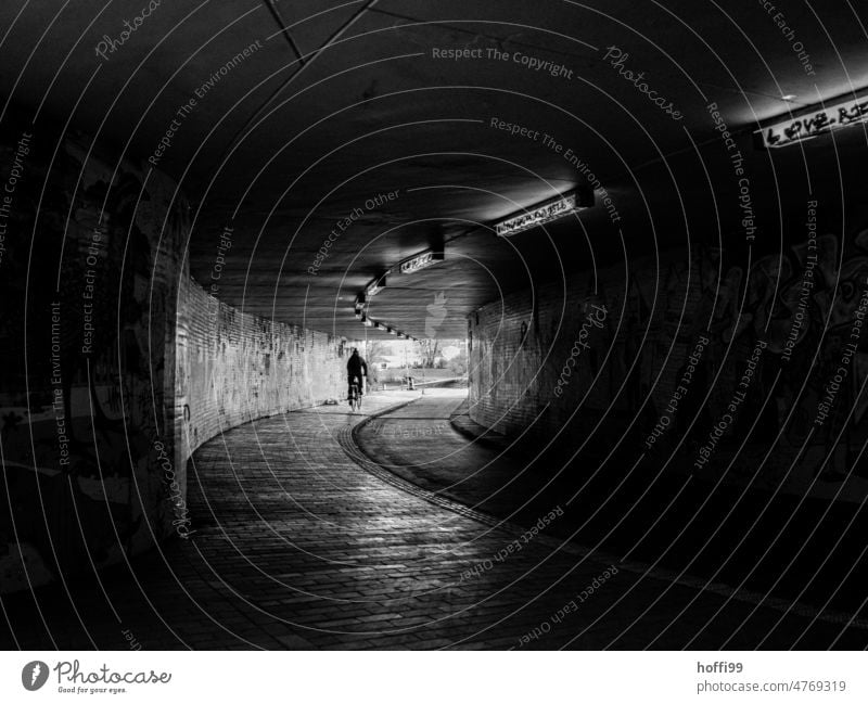 Radfahrer in einer Unterführung mit Licht am Ende des Tunnels Radfahren Radweg licht am ende des tunnels Wege & Pfade Gang dunkel Schatten schwarz Stimmung