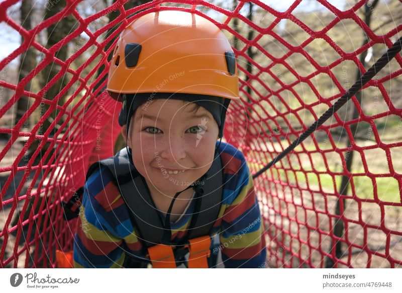 Frecher Junge beim Klettern klettern helm Netzwerk tunnel kindheit draußen abenteuer Freude frech Außenaufnahme Kindheit Natur Bewegung 3-8 Jahre Lifestyle