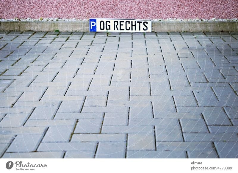Autonummernschild mit der Aufschrift  - P  OG Rechts -   am Rand einer gepflasterten Fläche / reservierter Parkplatz / Anwohnerparkplatz Pflastersteine Schild