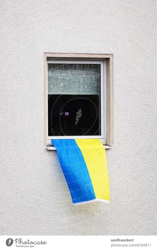 flagge der ukraine hängt am fenster eines wohnhauses - ein