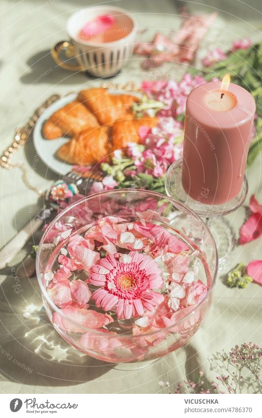 Ästhetisches Frühstück mit gläserner Wasserschale und rosa Blumen mit Kerze, Croissants und Teetasse Ästhetik Tasse Glas Wasserschüssel elegant Lebensmittel