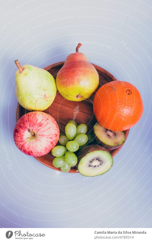 Sortiment von Früchten auf einem Holzteller und weißem Hintergrund. Ackerbau Amuse-Gueule Apfel sortiert Zitrusfrüchte lecker Dessert Diät anders essen