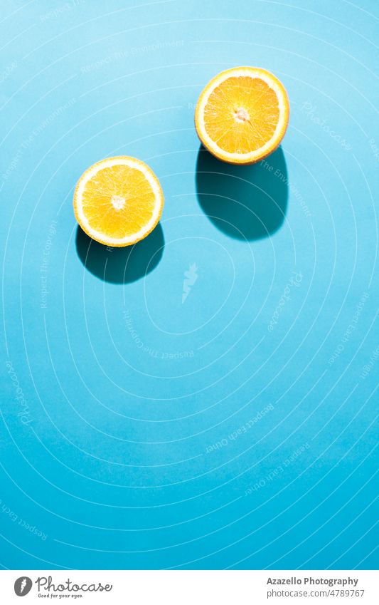 Einfaches Konzept flatlay zwei Stücke von Orange unter dem hellen Licht mit schwarzen Schatten auf blauem Hintergrund. Diät Pop-Art Taschenlampe Minimalismus