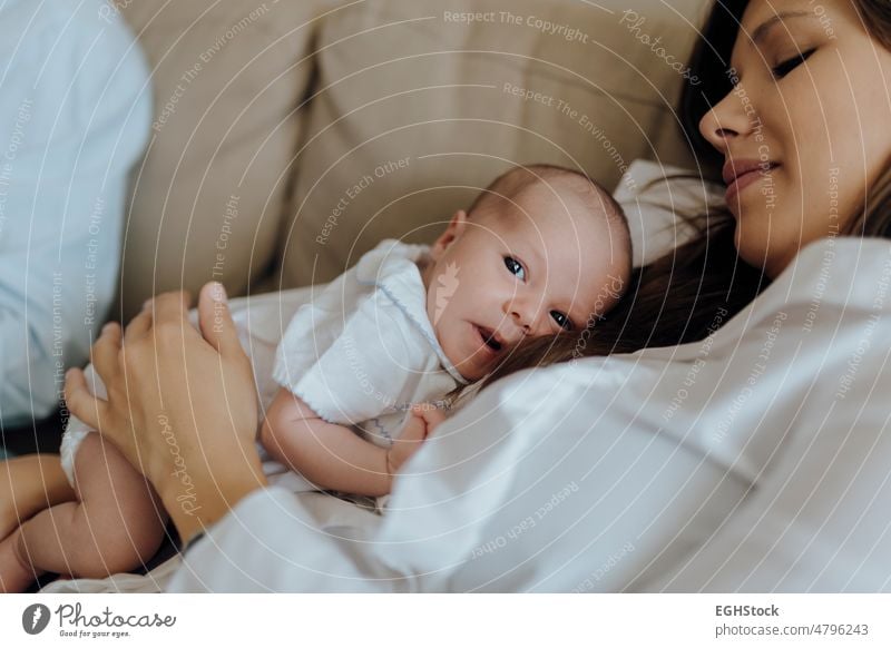 Neugeborener Junge schaut in die Kamera auf seine Mutter, die auf dem Sofa liegt neugeboren Baby Blick Fotokamera Mama Lügen Säugling bequem Kind