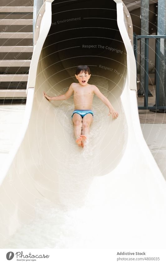 Niedliches Kind auf der Rutsche im Wasserpark an einem sonnigen Sommertag Junge Mitfahrgelegenheit Sliden unterhalten aqua Park aufgeregt Aktivität Kindheit