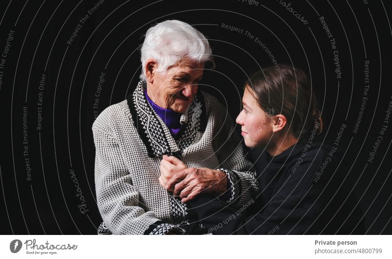 Ältere Frau sitzt mit einer erwachsenen Enkelin auf schwarzem Hintergrund. 80s Pflege Rentnerin Muttertag Großmutter Familie Zusammensein Erwachsener schön