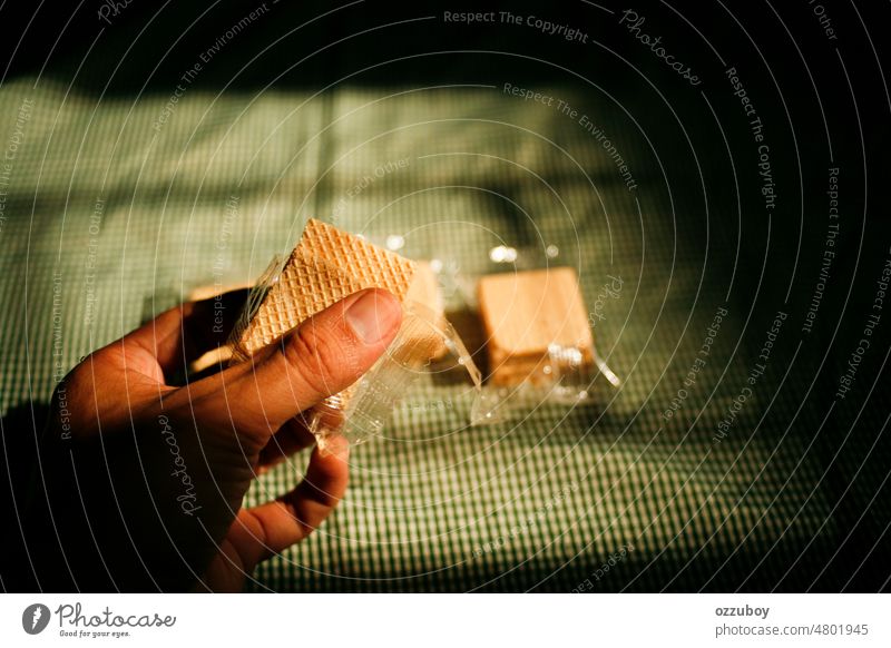 Eine Hand hält quadratische Waffelkekse in einer transparenten Plastikverpackung Wafer Lebensmittel Biskuit Keks Dessert Snack Sahne Schokolade Gebäck süß