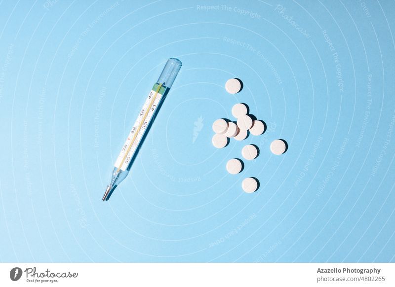Minimalistische Medizin und Gesundheitswesen Konzept Flatlay Pillen und ein Thermometer auf blauem Hintergrund. Medikamente Chemie Pharma weiß Tablette Dosis