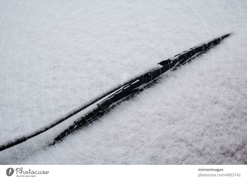 Autoscheibenwischer und eine schneebedeckte Windschutzscheibe Automobil Hintergrund schwarz PKW Auto-Scheibenwischer Nahaufnahme kalt Deckung auftauen