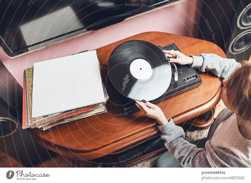 Junge Frau hört Musik von einem Schallplattenspieler. Retro und Vintage-Musik-Stil. Mädchen hält analoge Schallplatte Album. Frau genießt Musik aus alter Plattensammlung